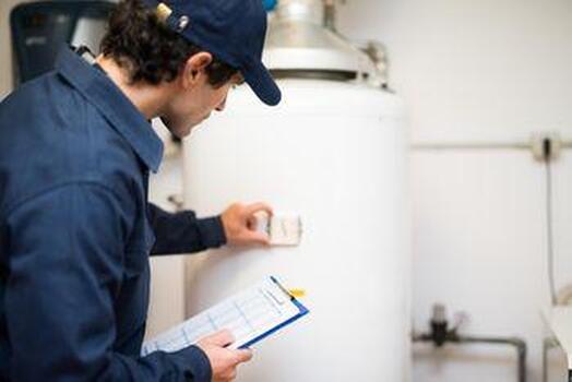 Picture of a licensed plumber inspecting a water heater tank