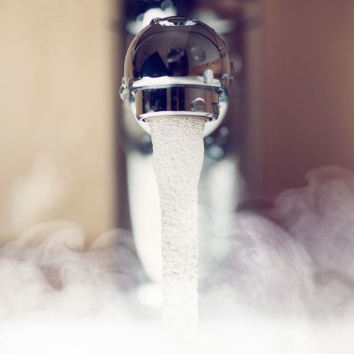 Picture of steaming hot water coming out of a sink faucet